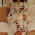 Woman wearing custom cat face pajama in light blue stripes, holding a fluffy cat on her lap
