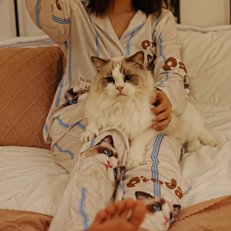 Woman wearing custom cat face pajama in light blue stripes, holding a fluffy cat on her lap